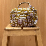vanity en coton matelassé imprimé en block print d'un motif floral violet, écru et rose pâle sur un fond vert olive
