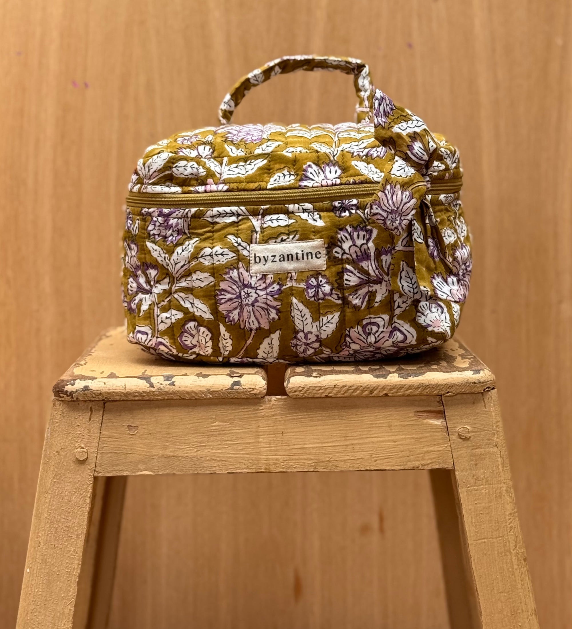vanity en coton matelassé imprimé en block print d'un motif floral violet, écru et rose pâle sur un fond vert olive