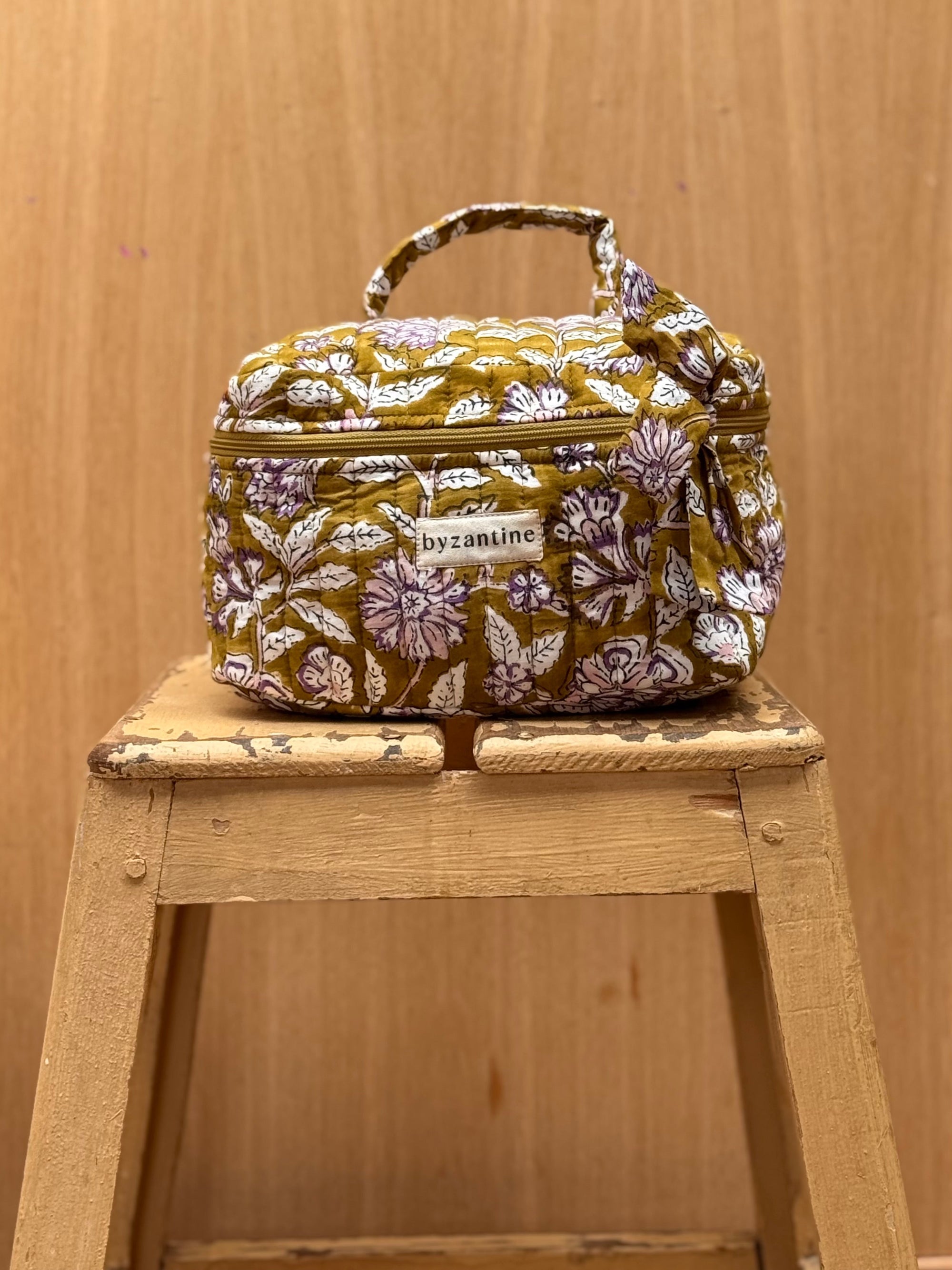 vanity en coton matelassé imprimé en block print d'un motif floral violet, écru et rose pâle sur un fond vert olive